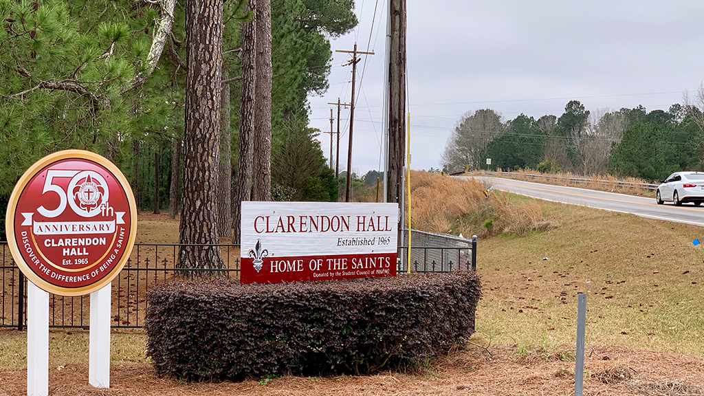 A sign marking the entrance of Clarendon Hall off an interstate. There's also a sign proclaiming the school's fiftieth anniversary.