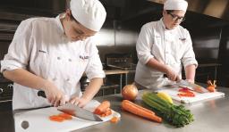Culinary students chop vegetables