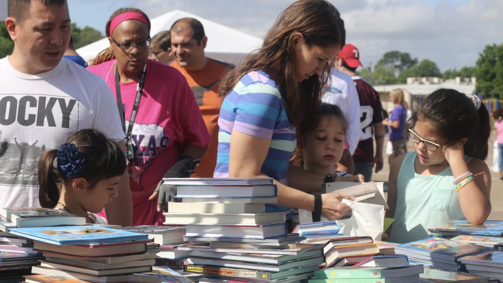 Students and their families pick books out from several large stacks