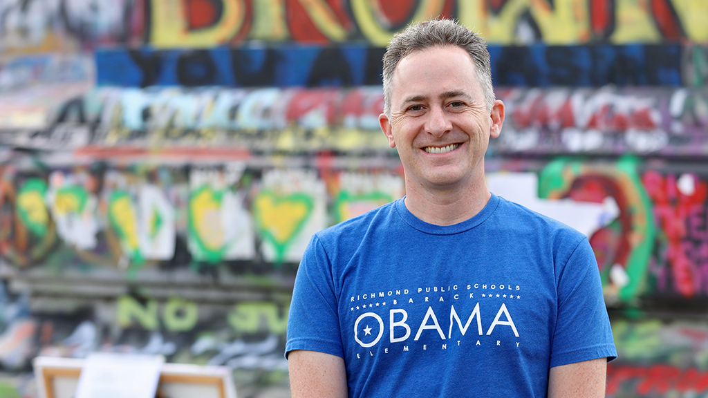 Jason Kamras smiles in front of a graffitied statue