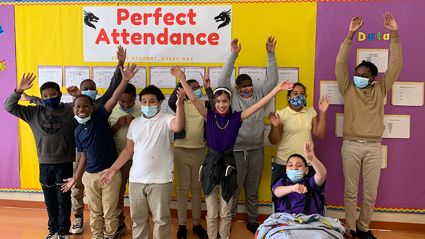 A group of smiling students stand in front of a sign that says 'Perfect Attendance."