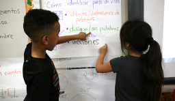 Two students look at words written on a wall chart