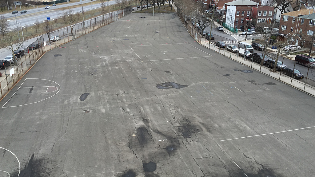 A 'Before' photo of a barren asphalt New York playground