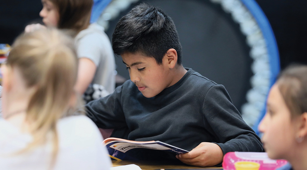 A boy reads a workbook in a classroom 