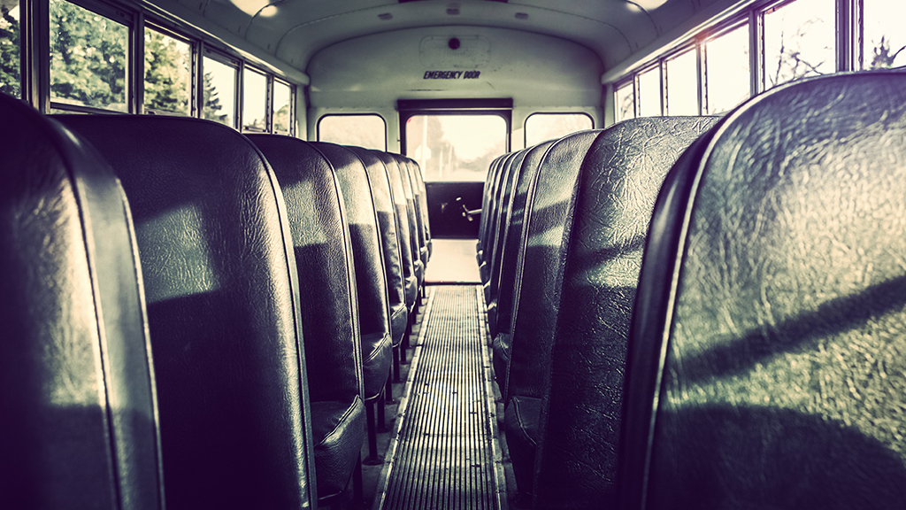 The sun shines inside a school bus with no students.