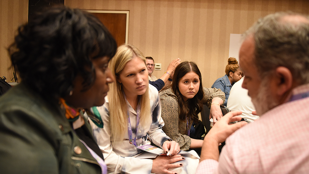 A small group of conference attendees engage in a discussion during a conference session.