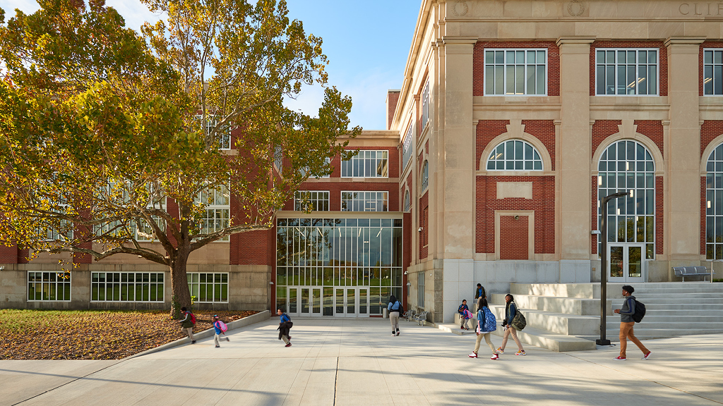 Students walk toward the entrance of a large, recently renovated school building.