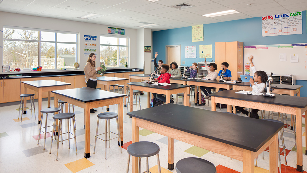 Students sit at new desks in the bright and airy science lab in a recently renovated school building. 