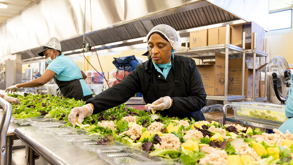 A school cafeteria worker prepares lunch salads. 