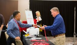 An NSBA staff member hands over registration materials to a conference attendee 